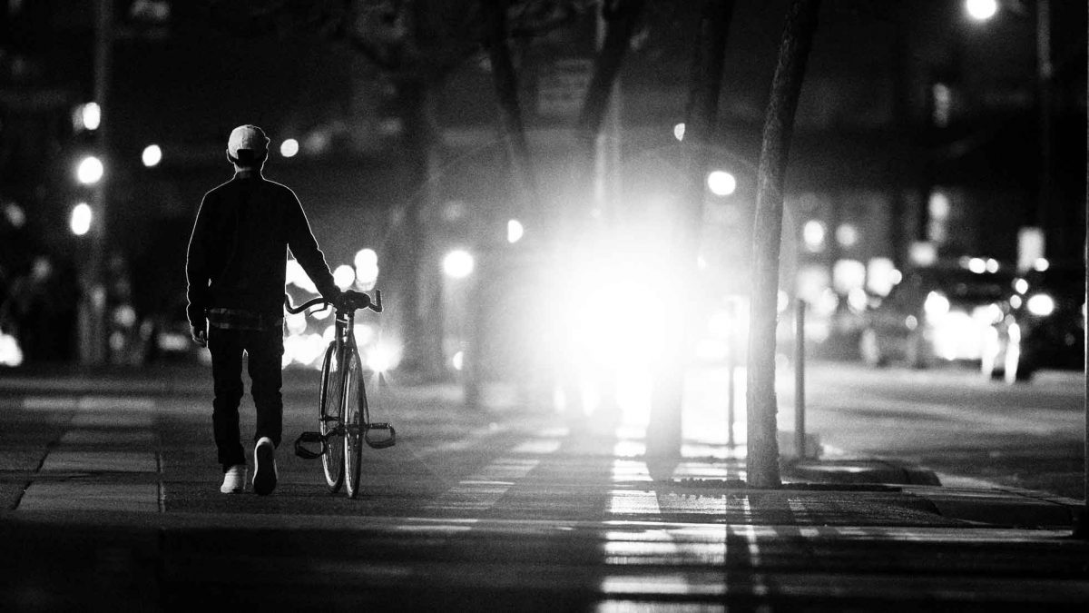 ciclista urbano iluminado por los faros de un coche